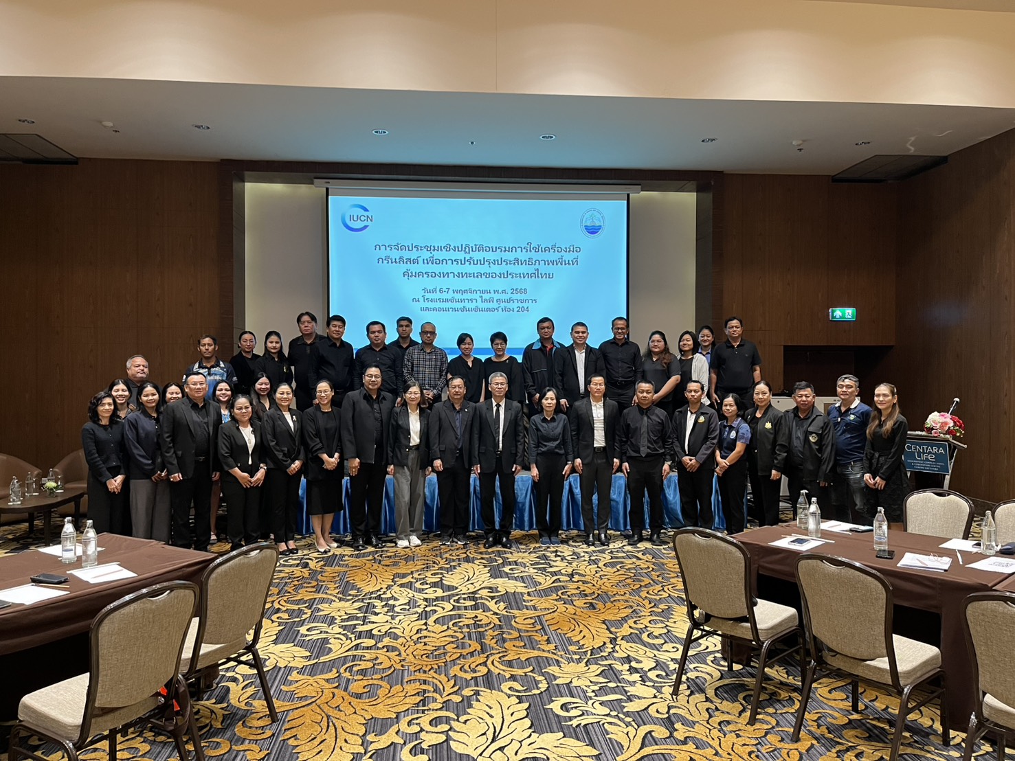 Rows of people lined up in front of a screen for a picture